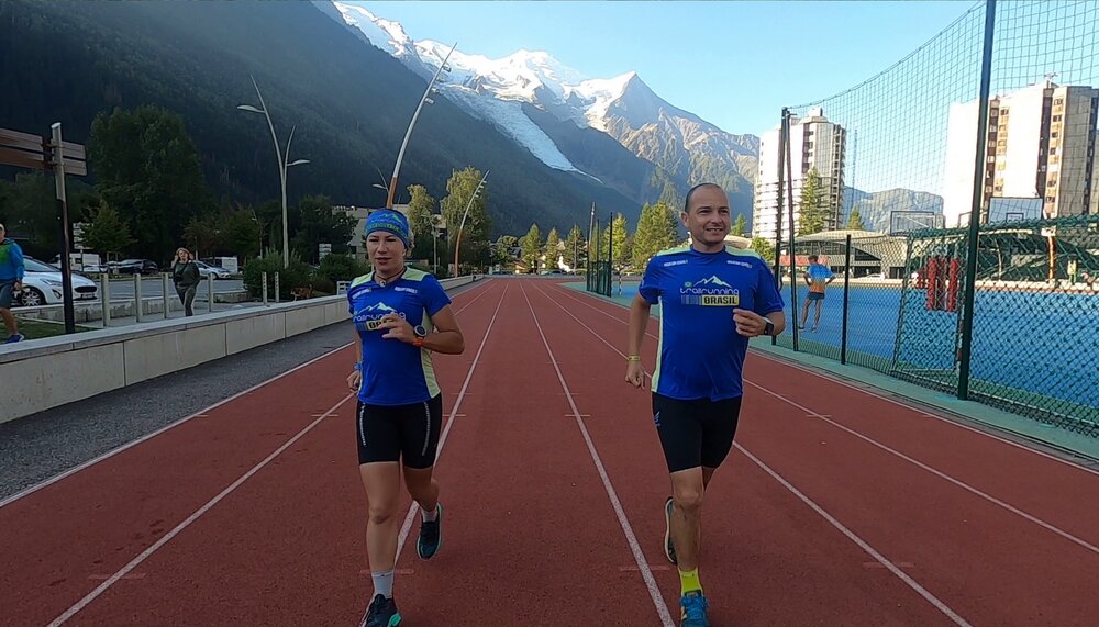 Marco e Letícia correndo juntos na pista de Chamonix com Mont Blanc ao fundo