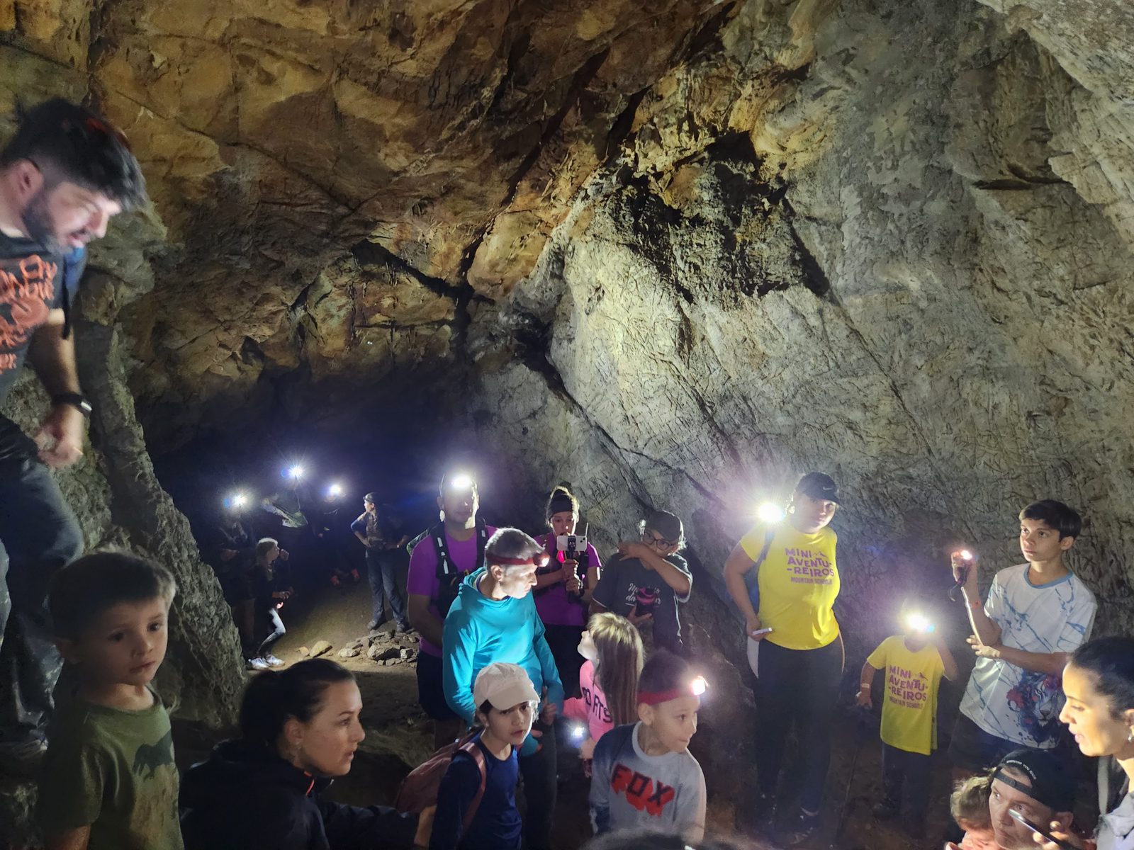 Crianças explorando caverna com lanternas
